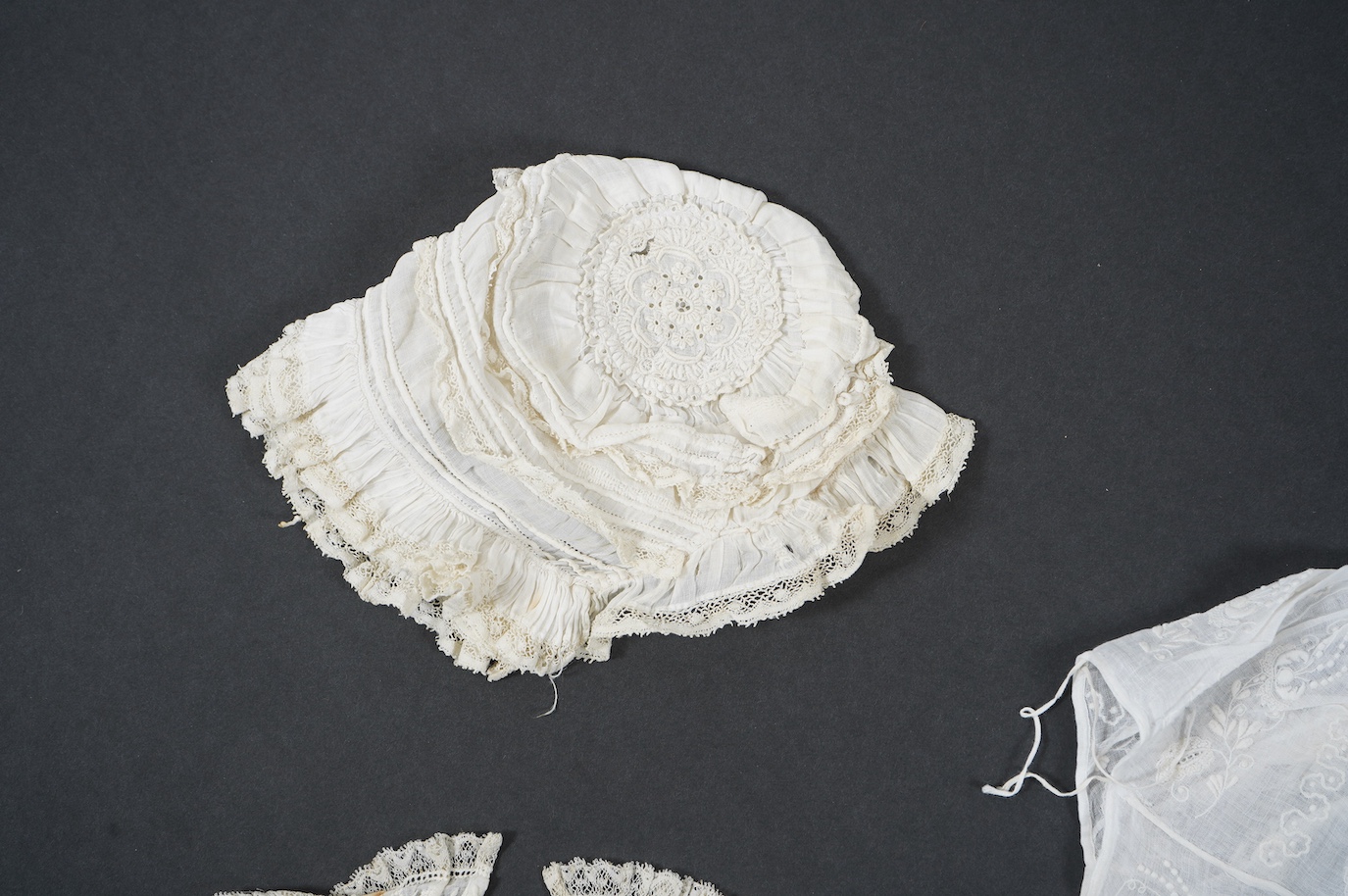 An 18th century Holly Point needle lace panelled linen baby bonnet, an early 19th century white worked baby bib and bonnet and a later 19th century finely ruffed lace bonnet (4). Condition - Holly Point bonnet and bib ha